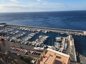Wide panoramic of Puerto de Radazul with moored boats, breakwater and open Atlantic.
