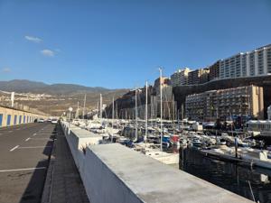 Promenade and road running beside the docks of Puerto de Radazul with mountains in the background.